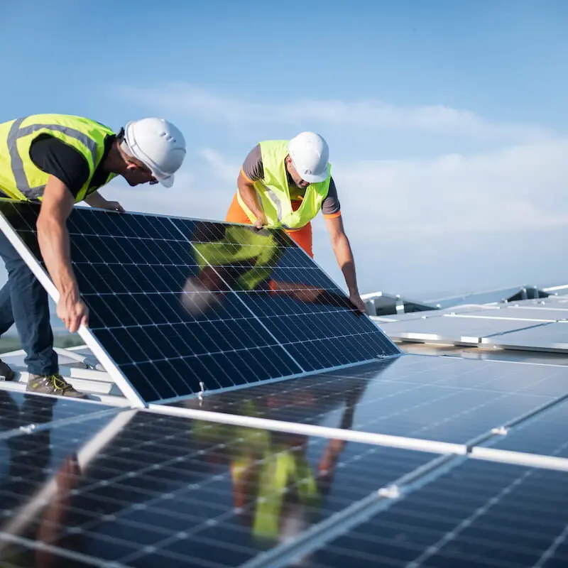 Twee elektriciens installeren zonnepanelen op een dak