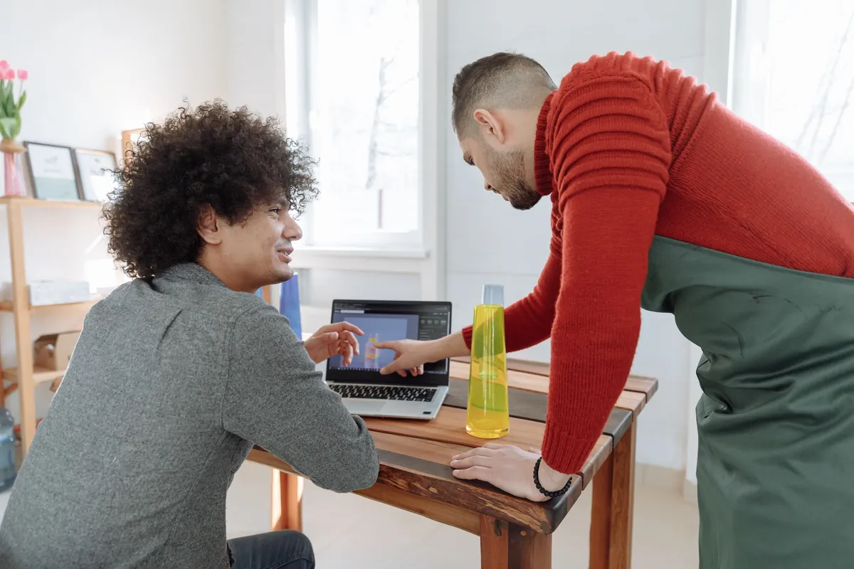 Twee mensen nemen samen iets door op een laptop in een licht kantoor